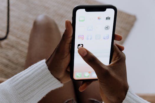 Close-up of hands with a smartphone using the TikTok app indoors, reflecting modern mobile technology.